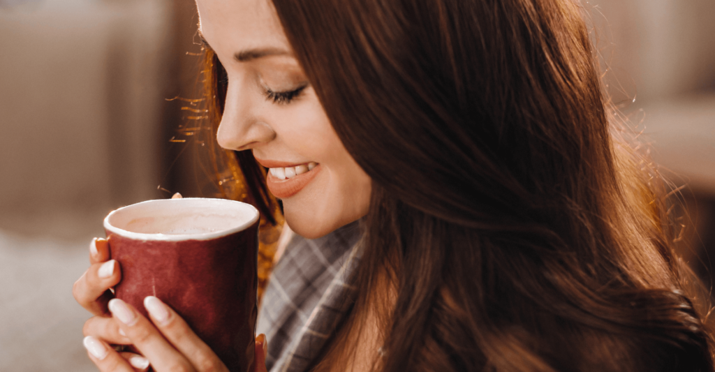 woman smiling while enjoying a cup of coffee